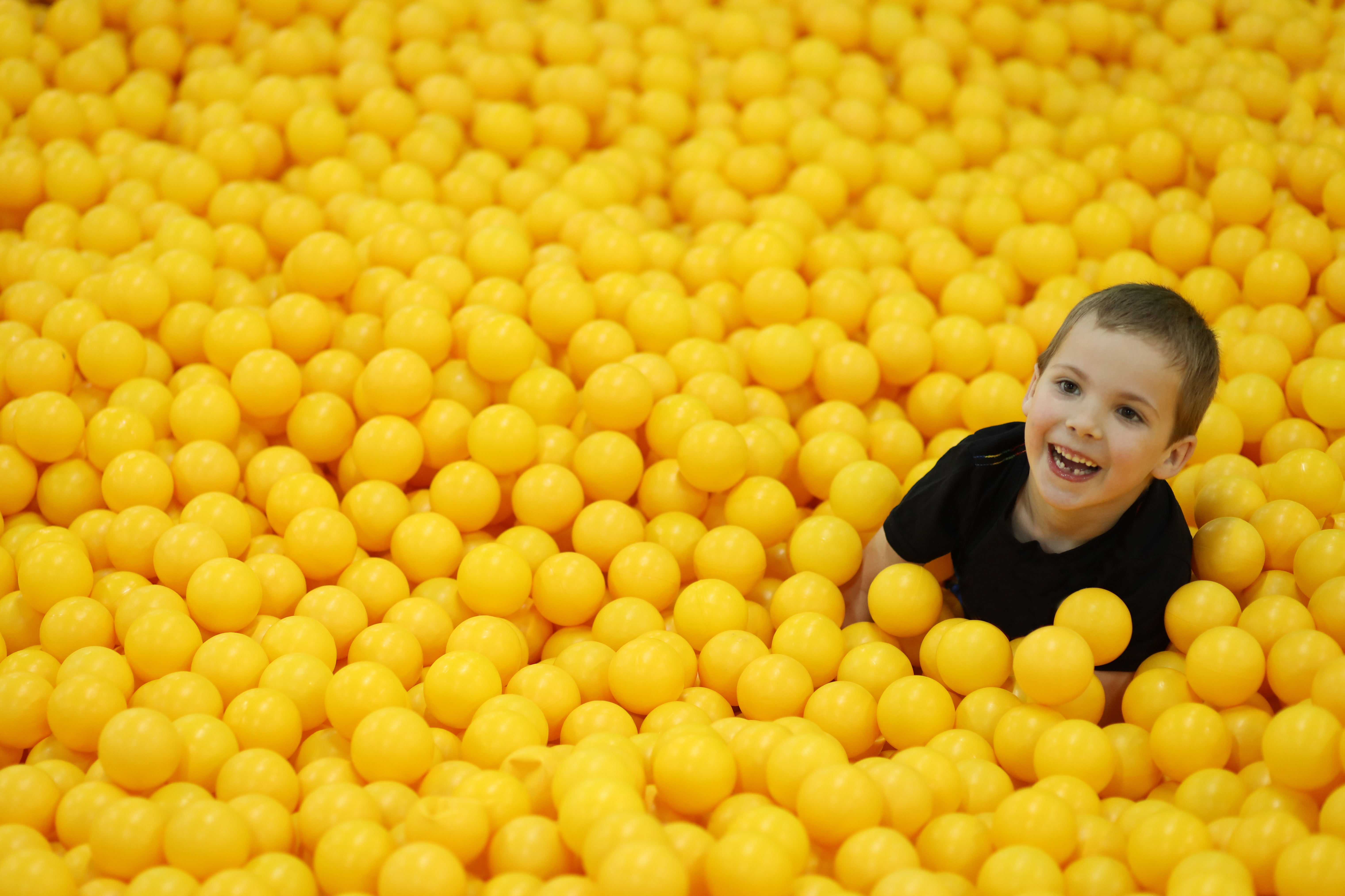 Play Matters — boy face-down in a pool of yellow play balls